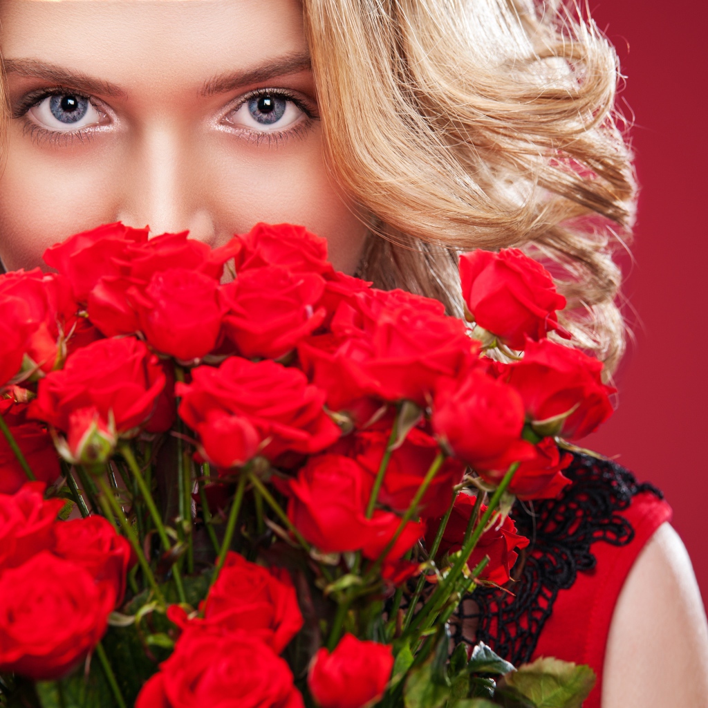 Красивая голубоглазая блондинка с букетом красных роз 