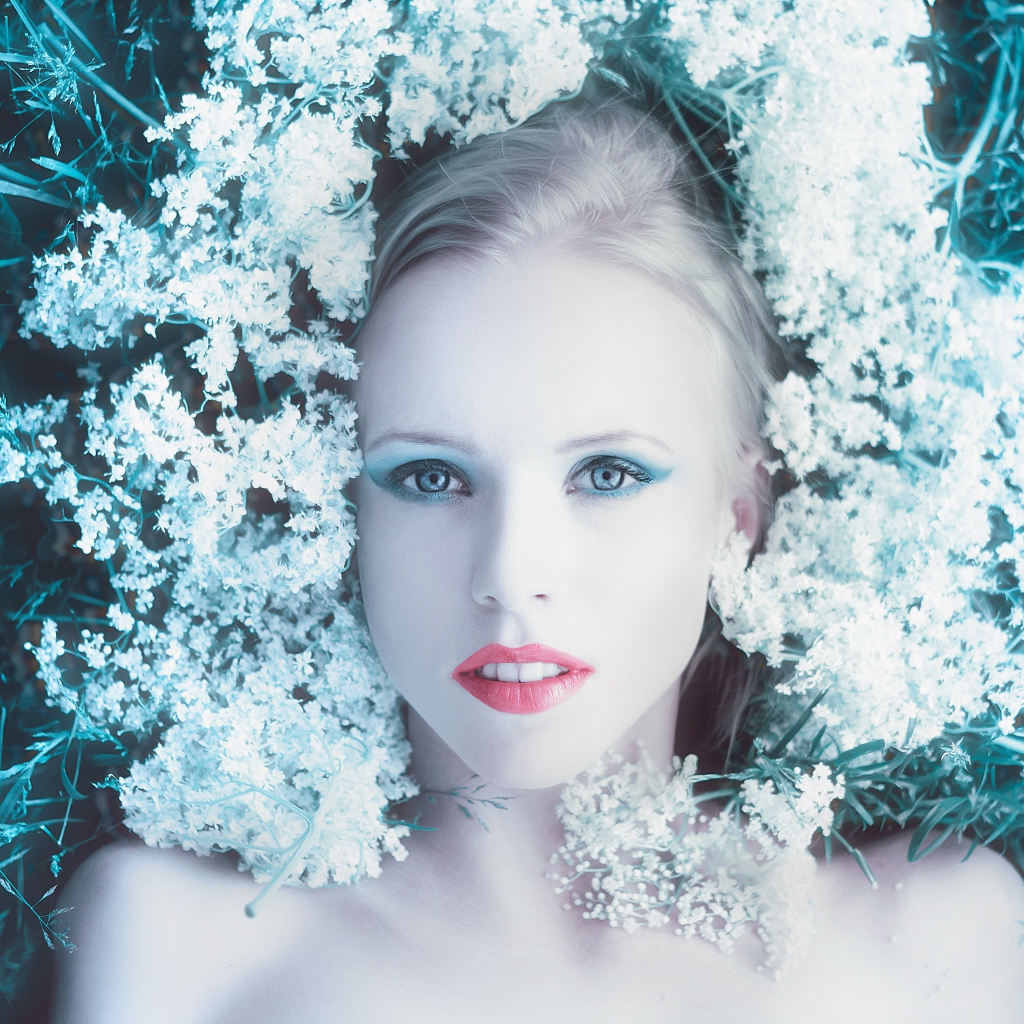 Красивая голубоглазая девушка на траве с белыми цветами