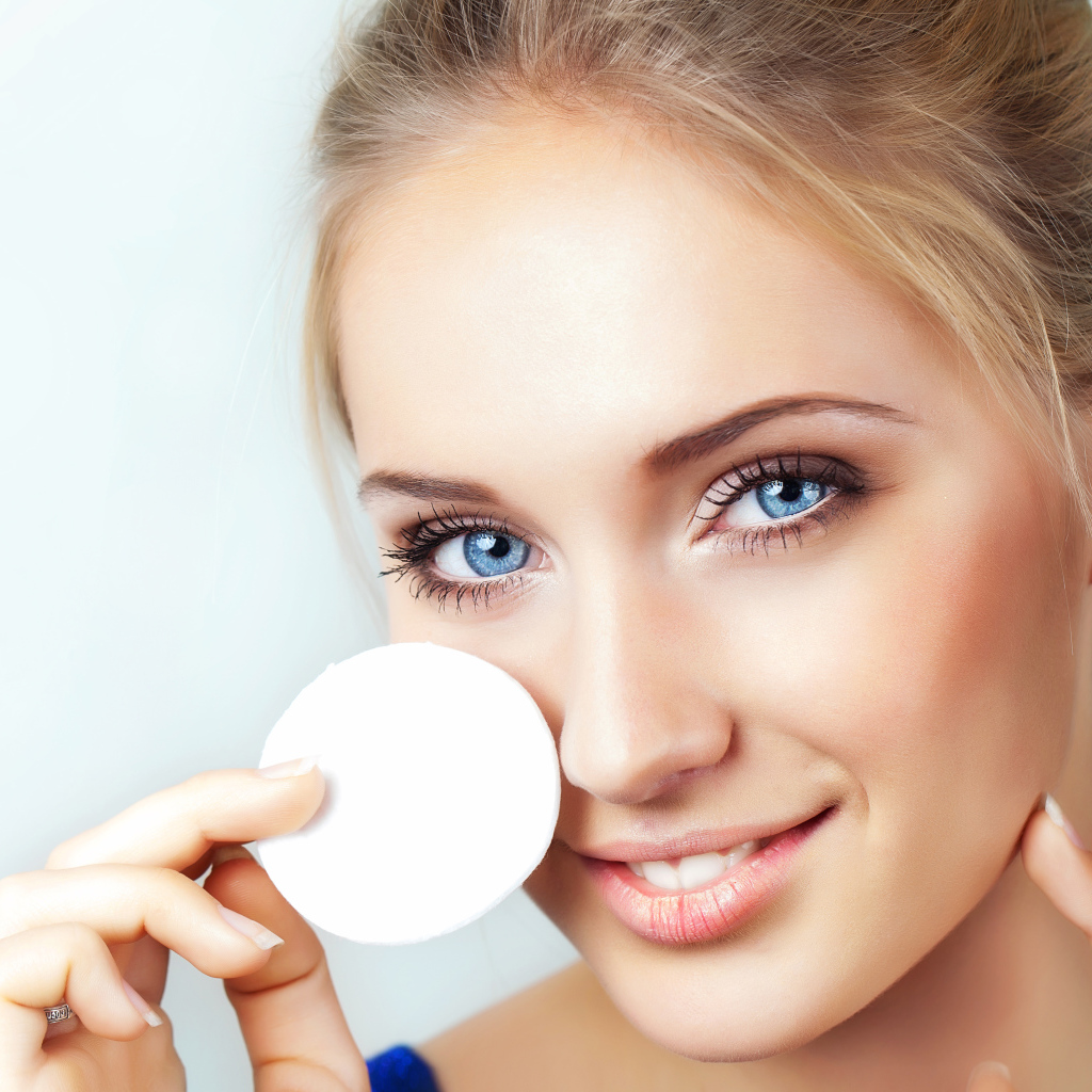 Красивая голубоглазая девушка с ватным диском в руке 