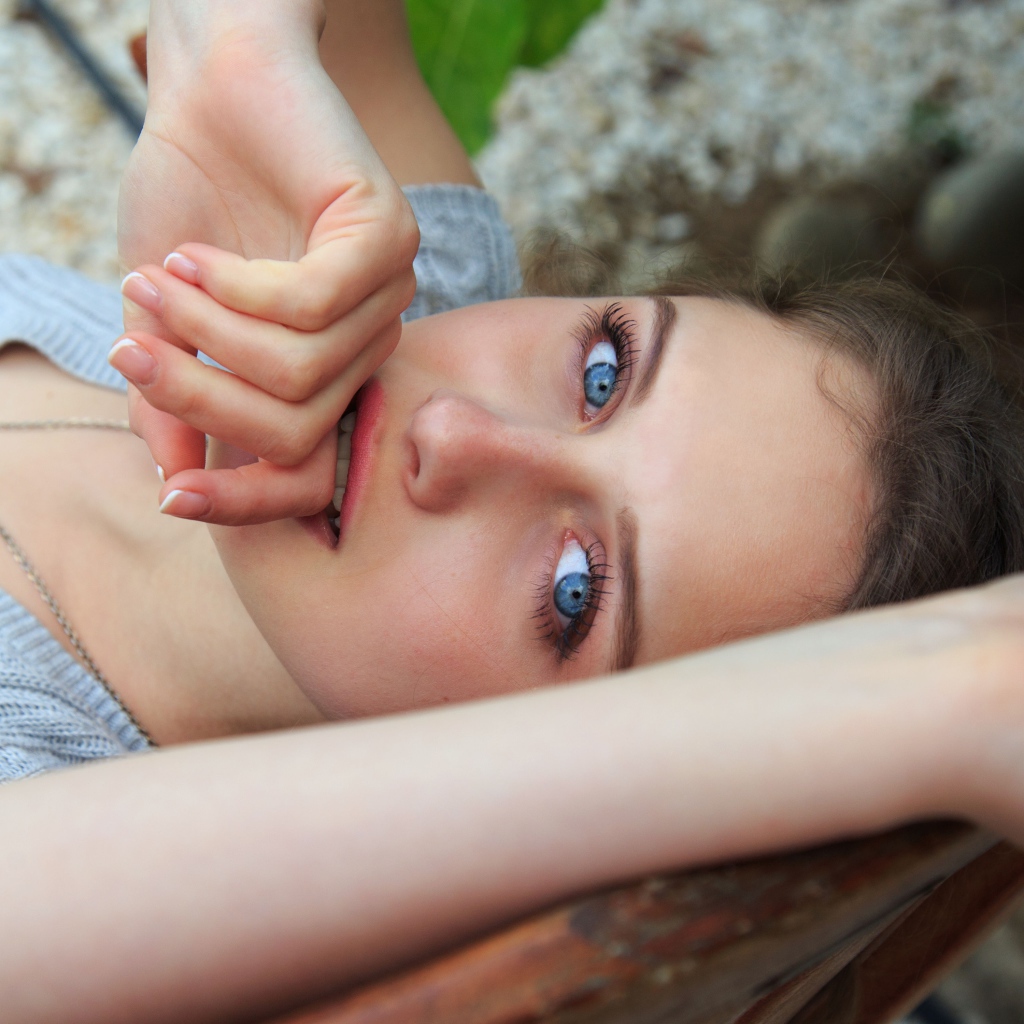 Красивая голубоглазая девушка с рукой у рта