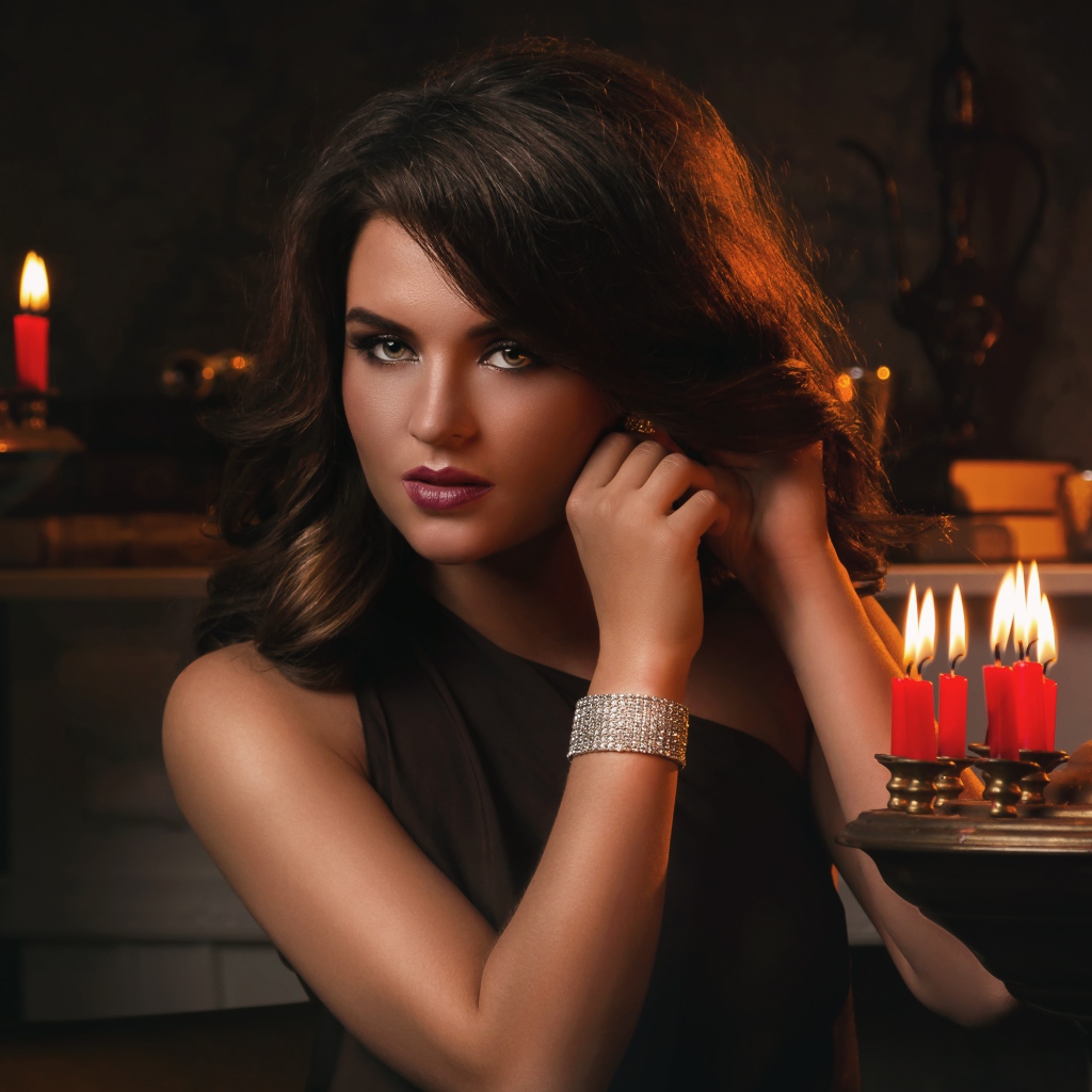 Красивая брюнетка в черном платье и зажженными свечами