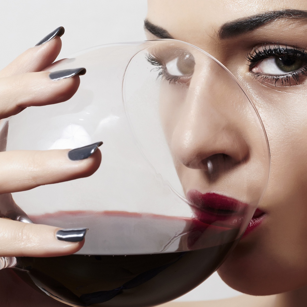 Красивая девушка пьет вино из бокала 