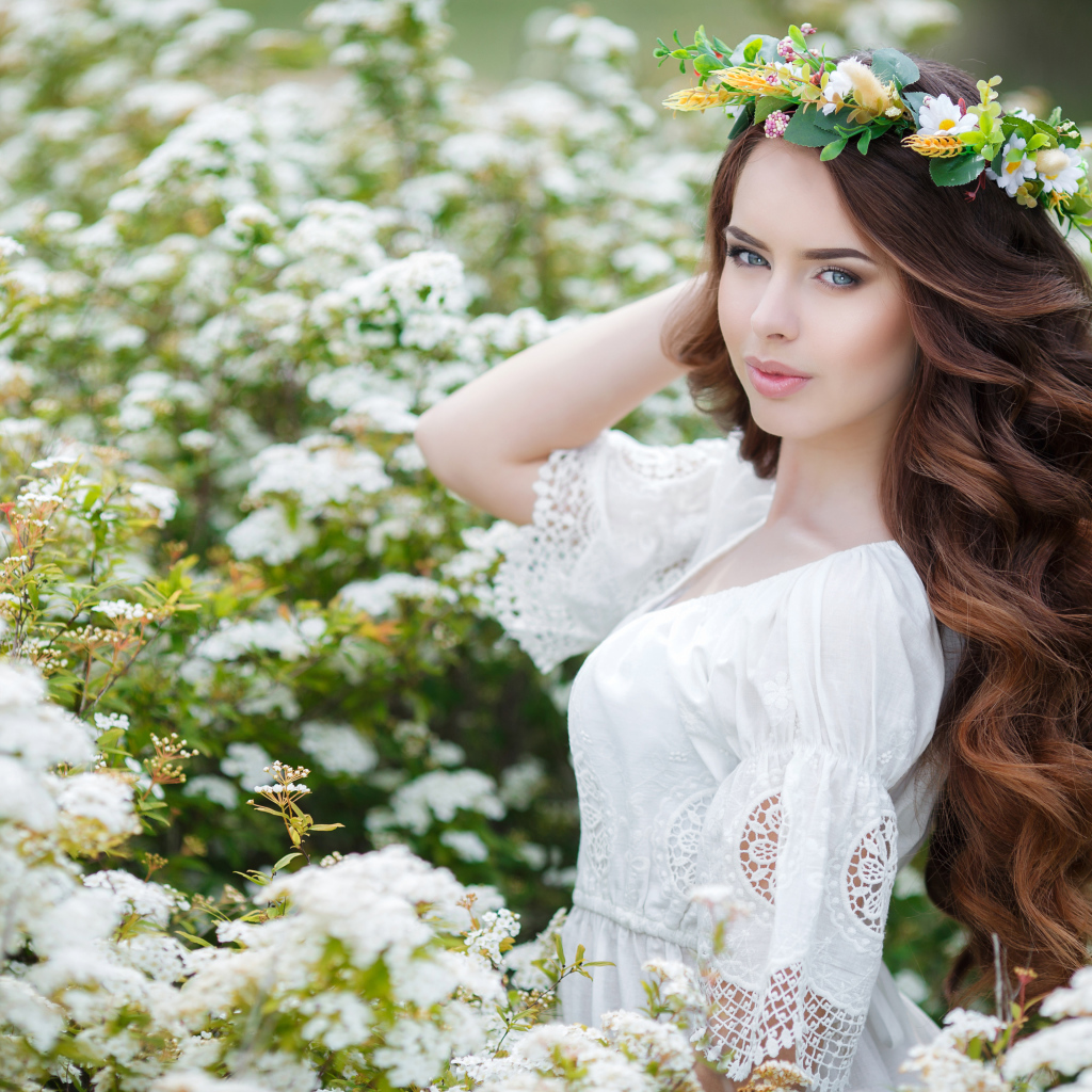 Красивая девушка в платье у куста с белыми цветами