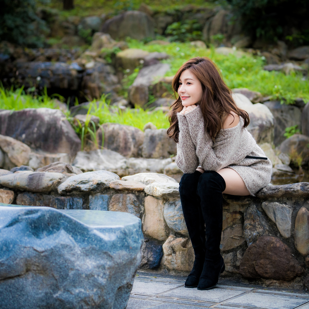 Красивая девушка в кофте сидит у пруда