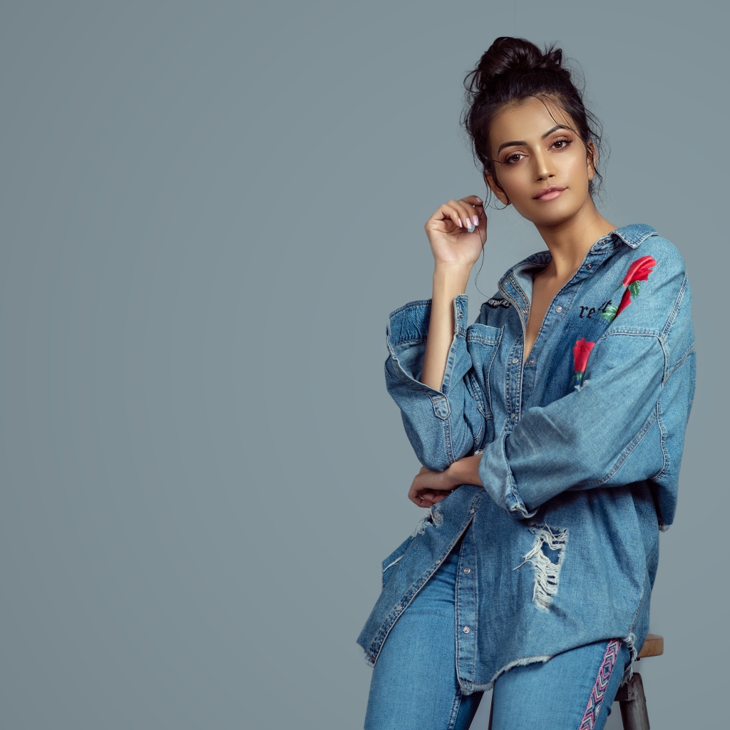 Красивая девушка в джинсовом костюме на сером фоне