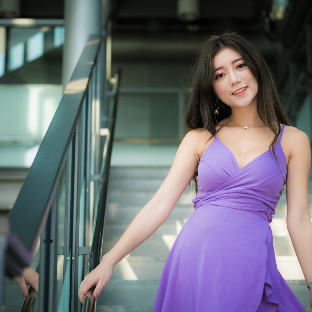 Beautiful girl in a lilac dress stands on the steps