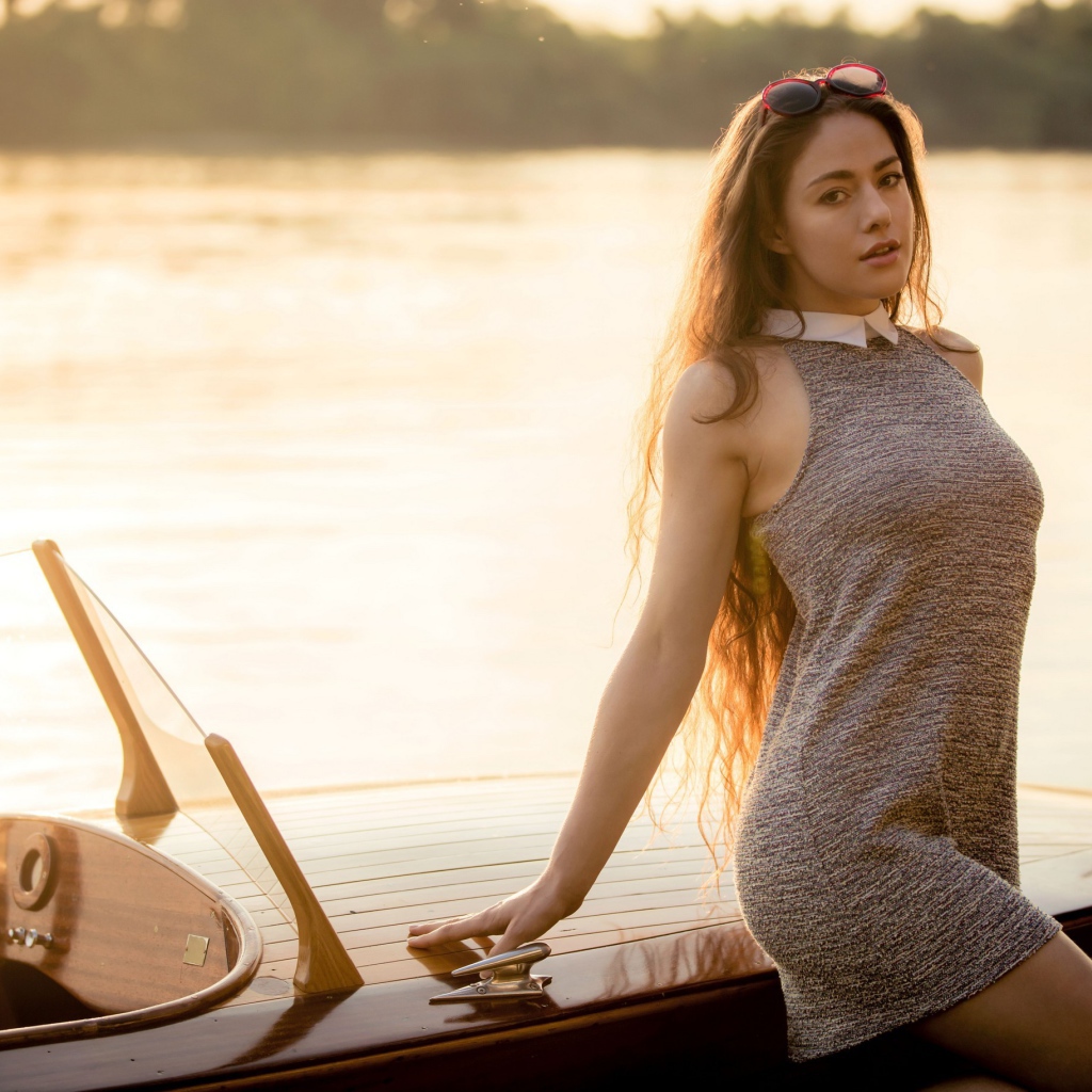 Красивая девушка в коротком платье стоит у катера 