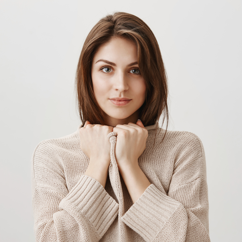 Красивая девушка в теплом свитере на сером фоне 
