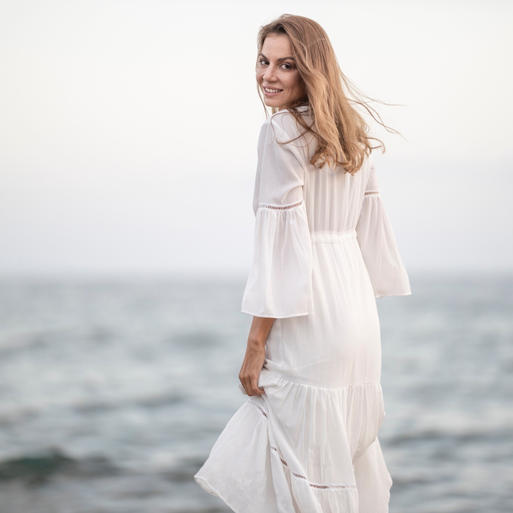 Красивая девушка в белом платье у моря