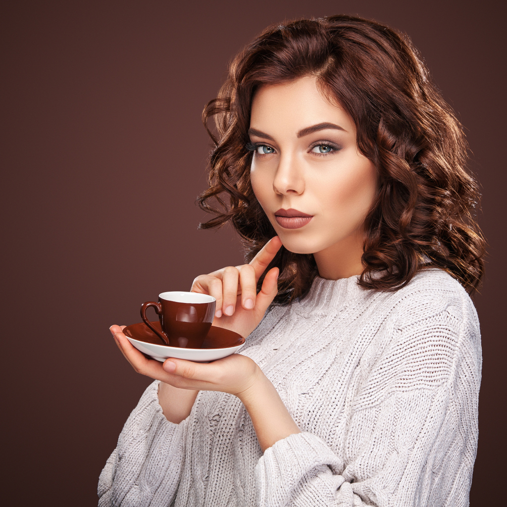 Красивая девушка в белом свитере с чашкой кофе