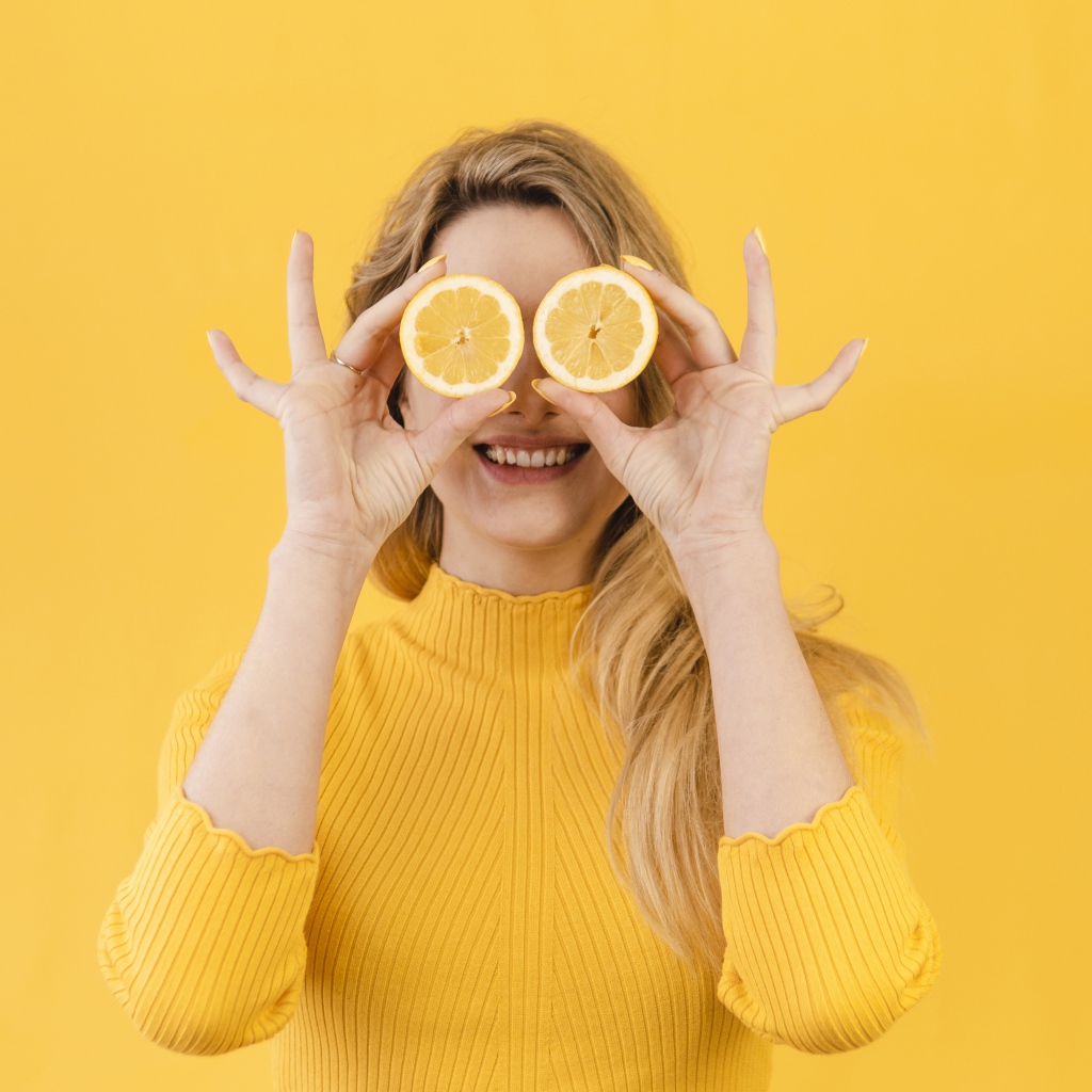 Красивая девушка в желтом свитере с лимоном