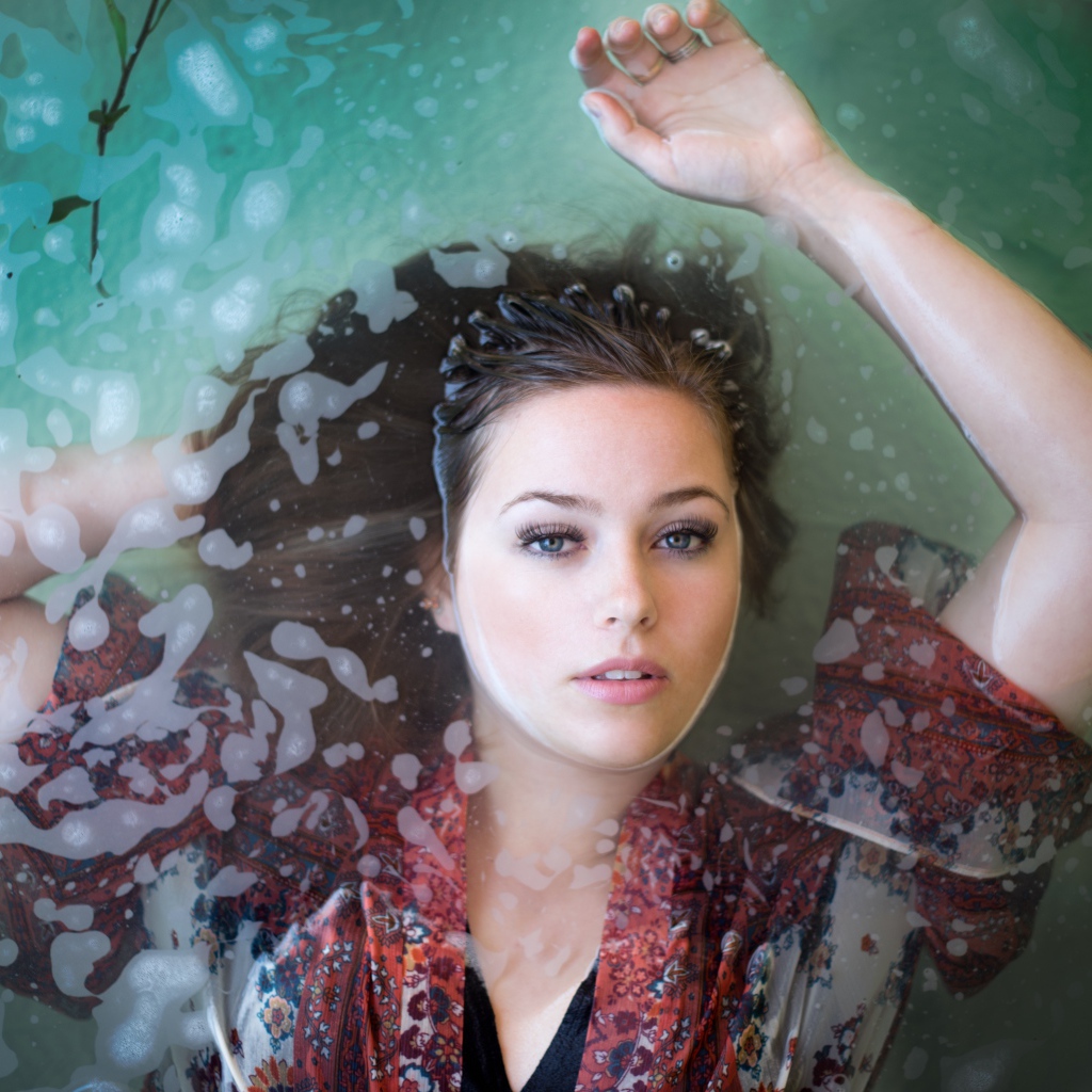 Красивая девушка лежит в одежде в воде 