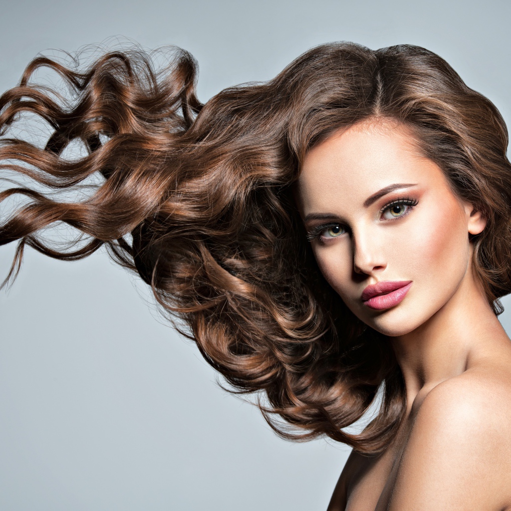 Красивая девушка модель с волнистыми волосами на сером фоне