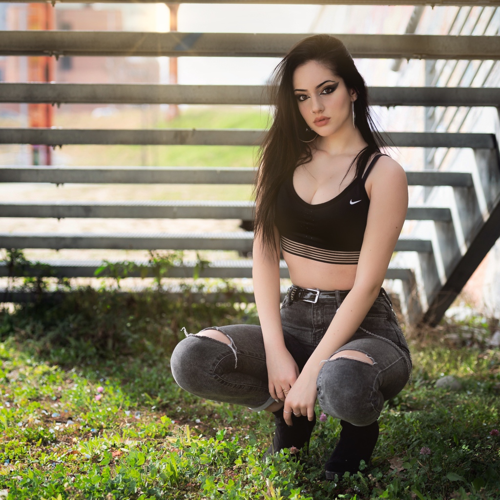 Красивая девушка сидит под лестницей 