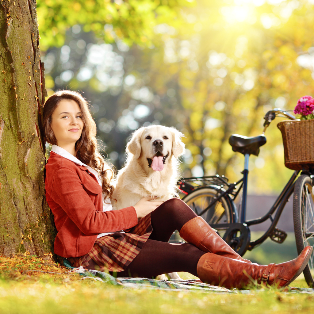 Красивая девушка сидит с собакой у дерева 