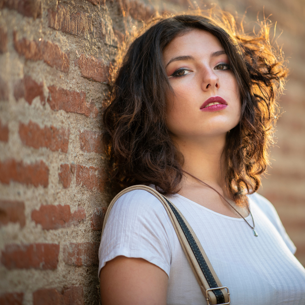 Красивая девушка стоит у стены 