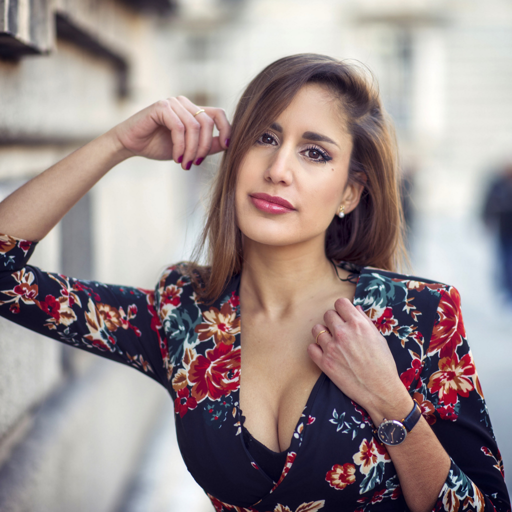 Красивая девушка с часами на руке стоит у стены