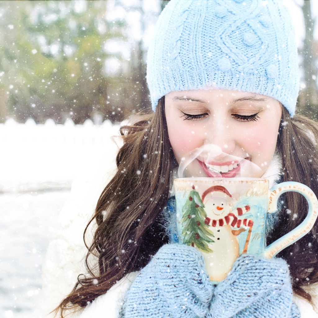Красивая девушка с чашкой горячего кофе на улице зимой