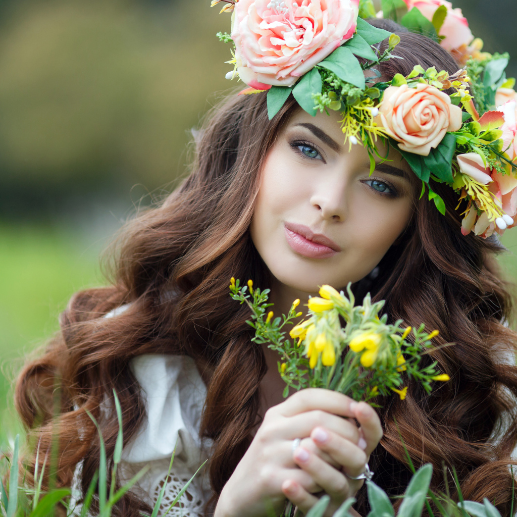 Красивая девушка с венком на голове лежит на зеленой траве