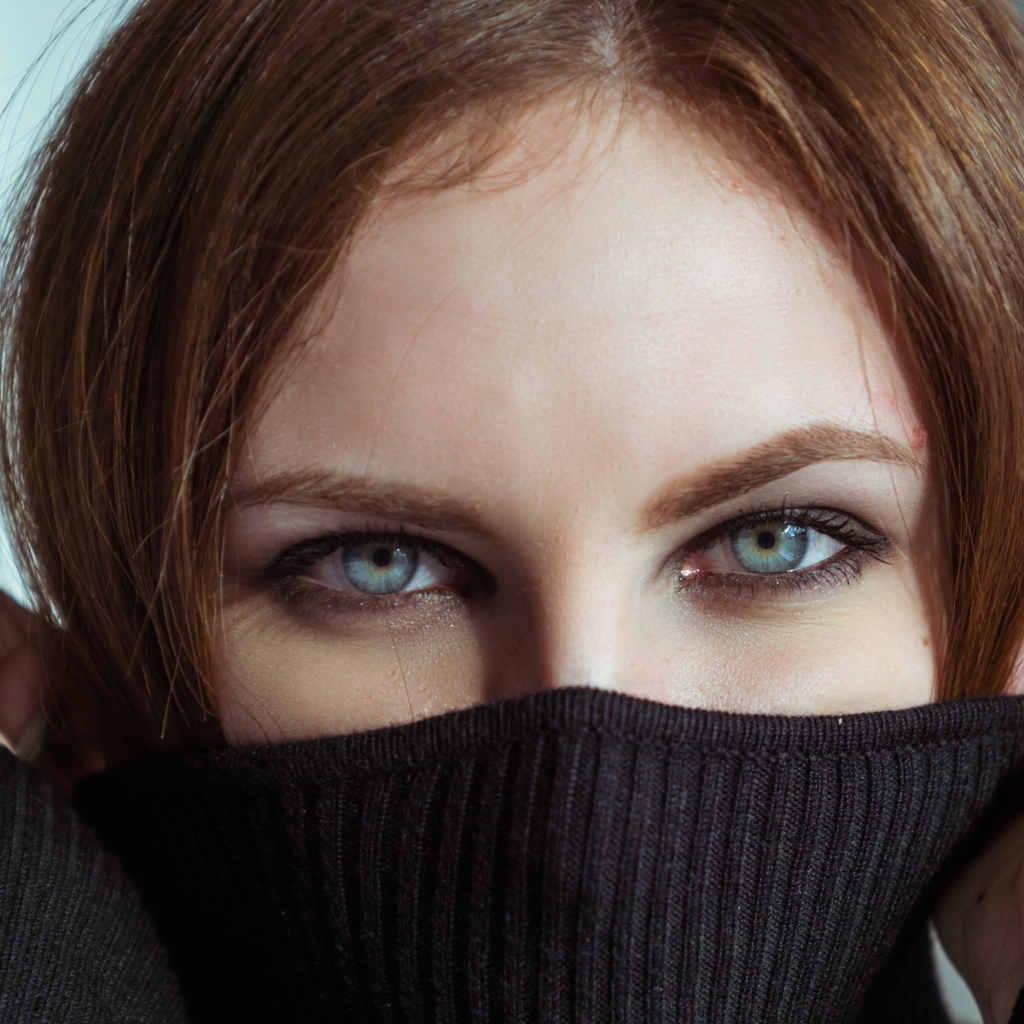 Красивая девушка с голубыми глазами закрыла лицо свитером 