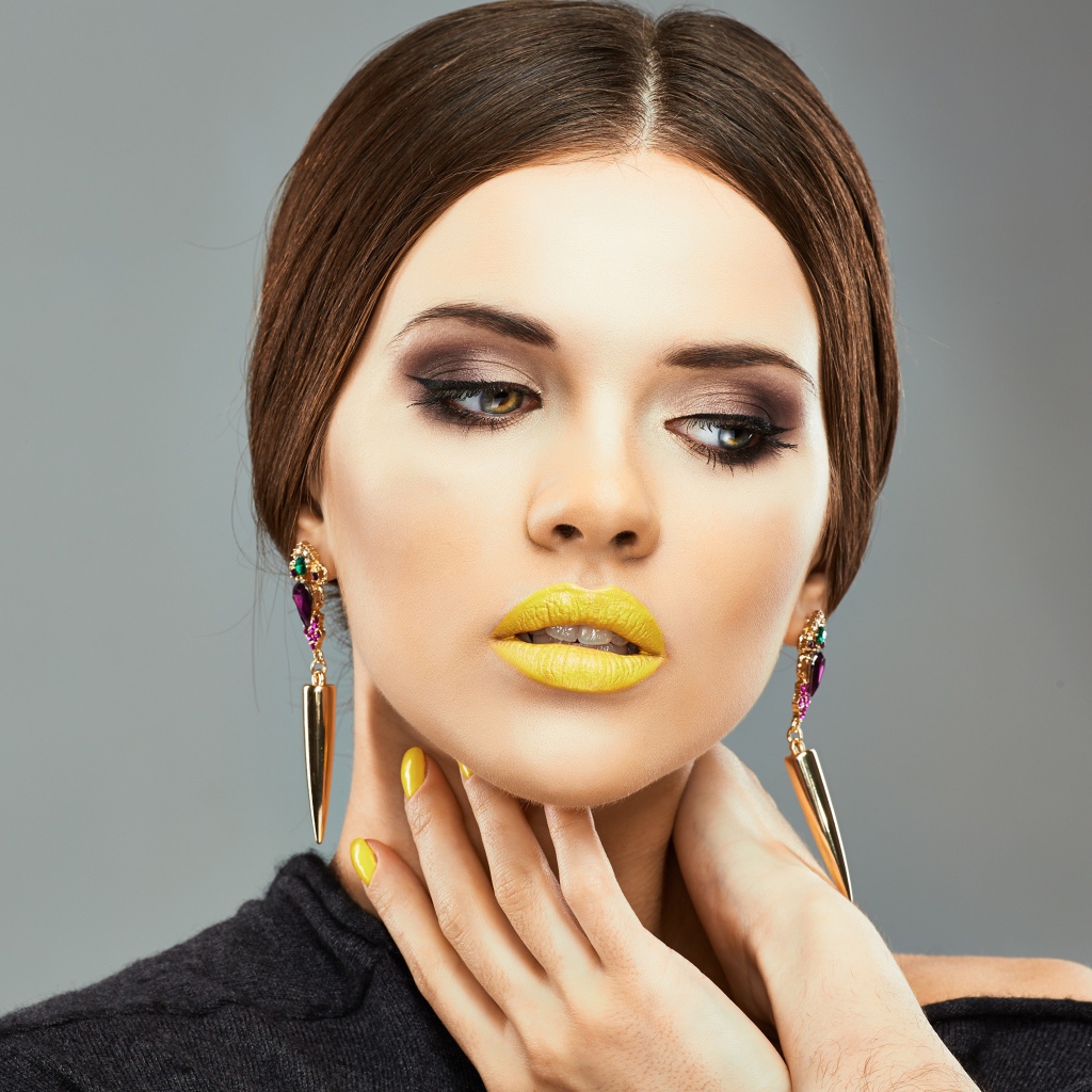 Красивая девушка с дорогими серьгами в ушах на сером фоне