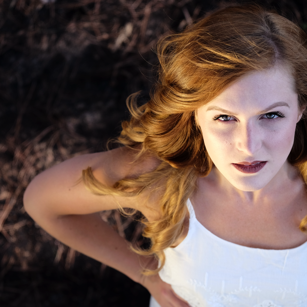 Красивый взгляд рыжеволосой девушки в белом платье