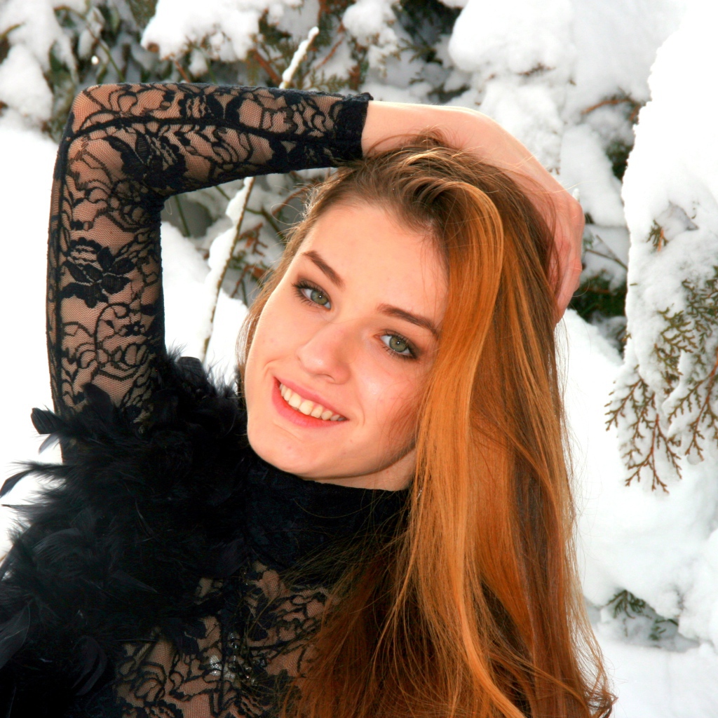 Красивая рыжеволосая девушка у заснеженной туи