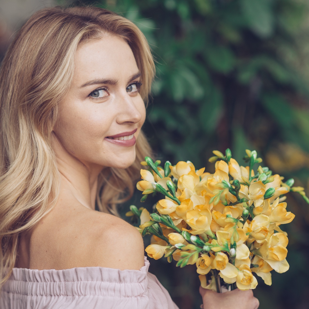 Красивая улыбающаяся девушка с букетом желтых цветов в руке 