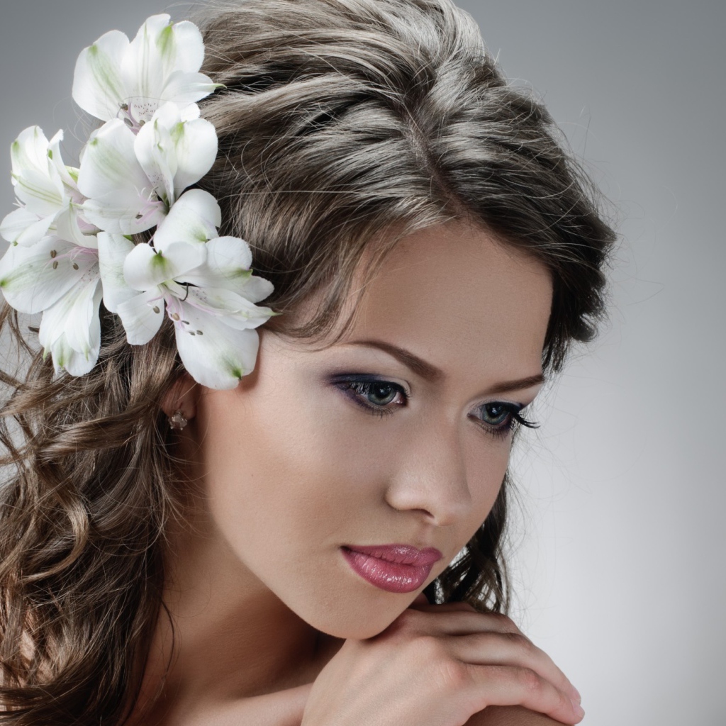 Красивая нежная девушка с белыми цветами в волосах на сером фоне
