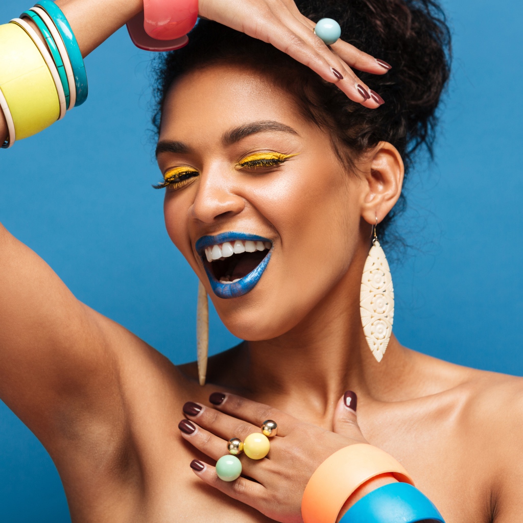 Красивая молодая девушка с ярким разноцветным макияжем на голубом фоне