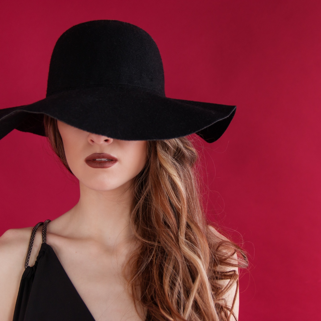 Большая черная шляпа закрывает лицо девушки
