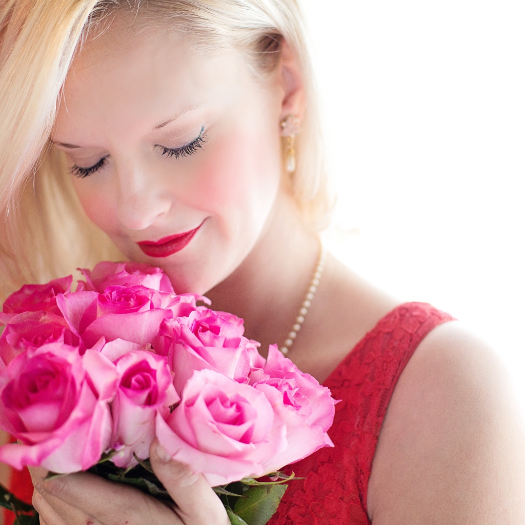 Блондинка с закрытыми глазами нюхает букет роз