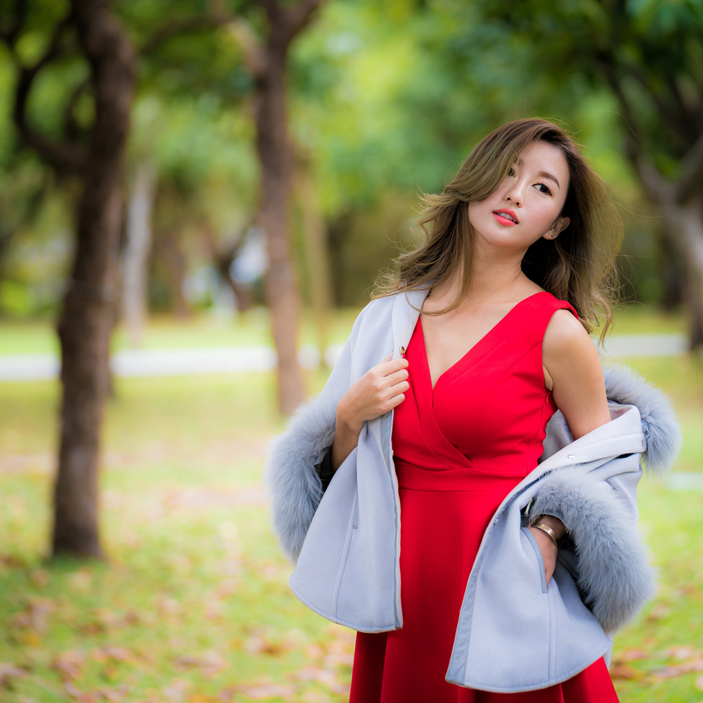 Яркая девушка азиатка в красном платье в парке