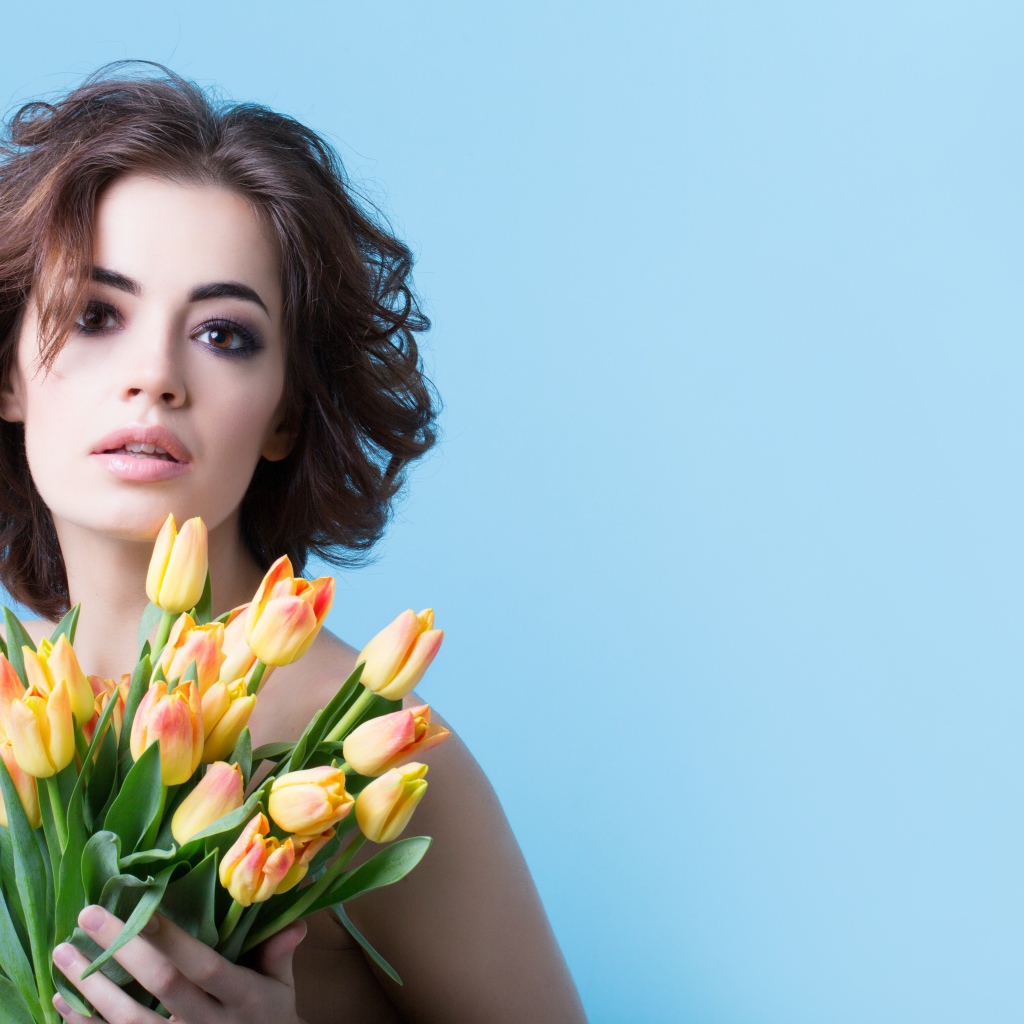 Кареглазая шатенка с букетом тюльпанов на голубом фоне