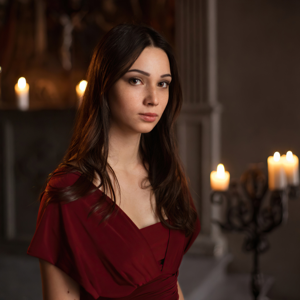 Кареглазая девушка в красном платье в комнате со свечами