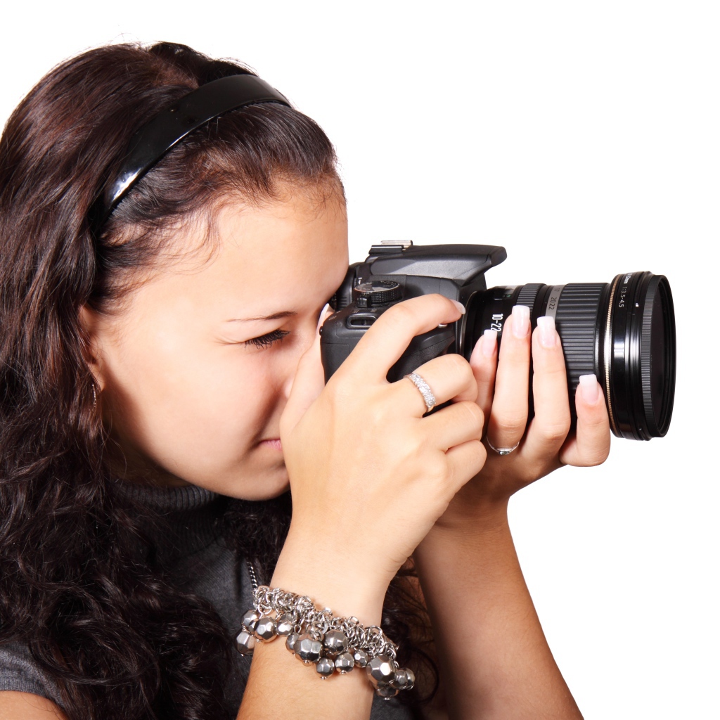 Молодая девушка шатенка с фотоаппаратом в руках на белом фоне