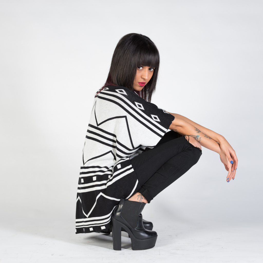 Брюнетка сидит на корточках 