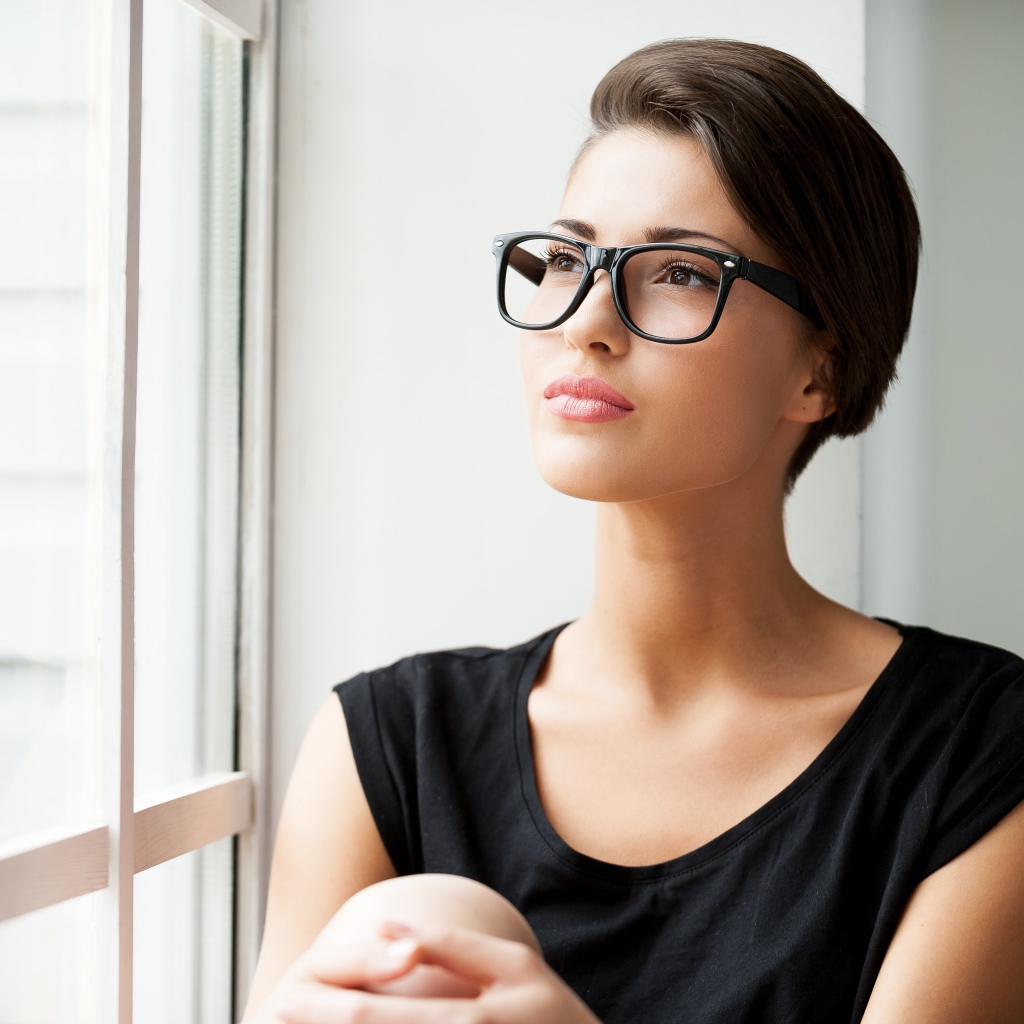 Деловая девушка в очках сидит у окна 