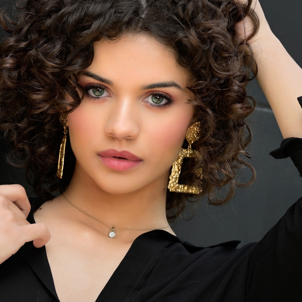 Кудрявая девушка с рукой в волосах в черной рубашке 