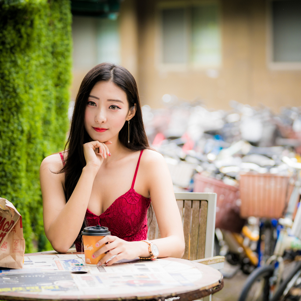 Милая девушка азиатка сидит за столиком в кафе