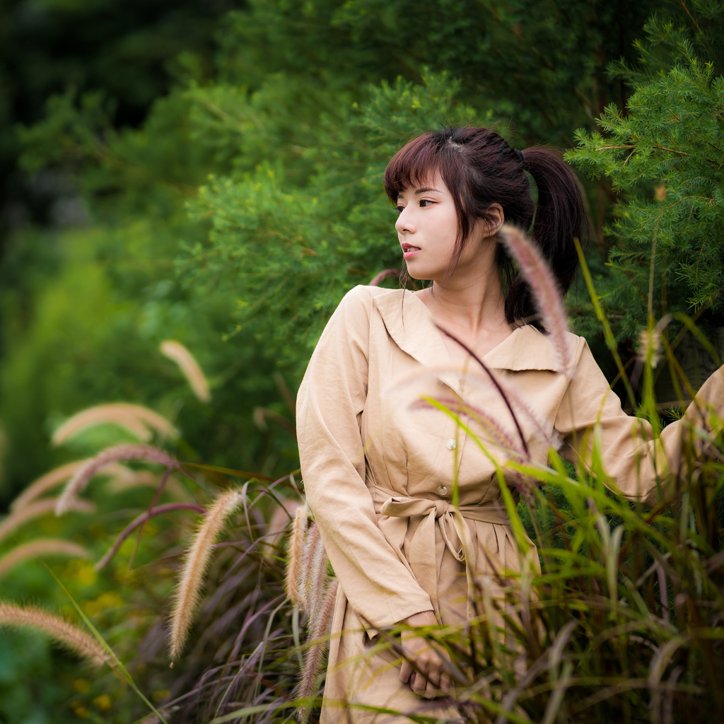 Милая азиатка в пальто в парке 