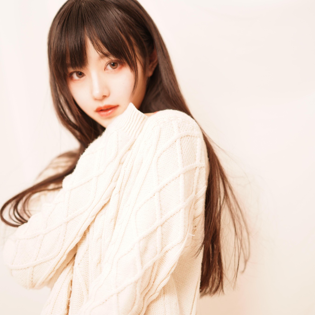 Милая азиатка в белом свитере на розовом фоне