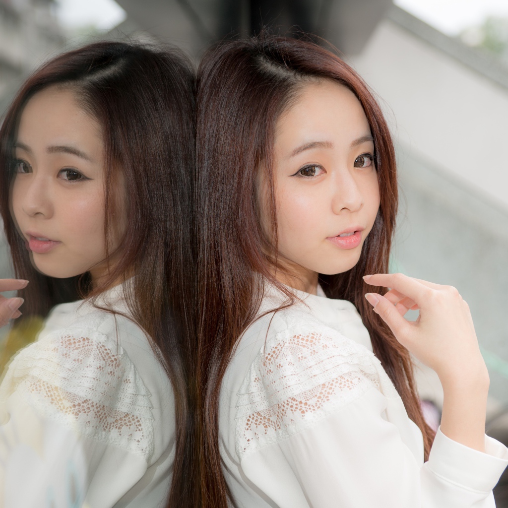 Милая азиатка в белой рубашке отражается в зеркальной поверхности 