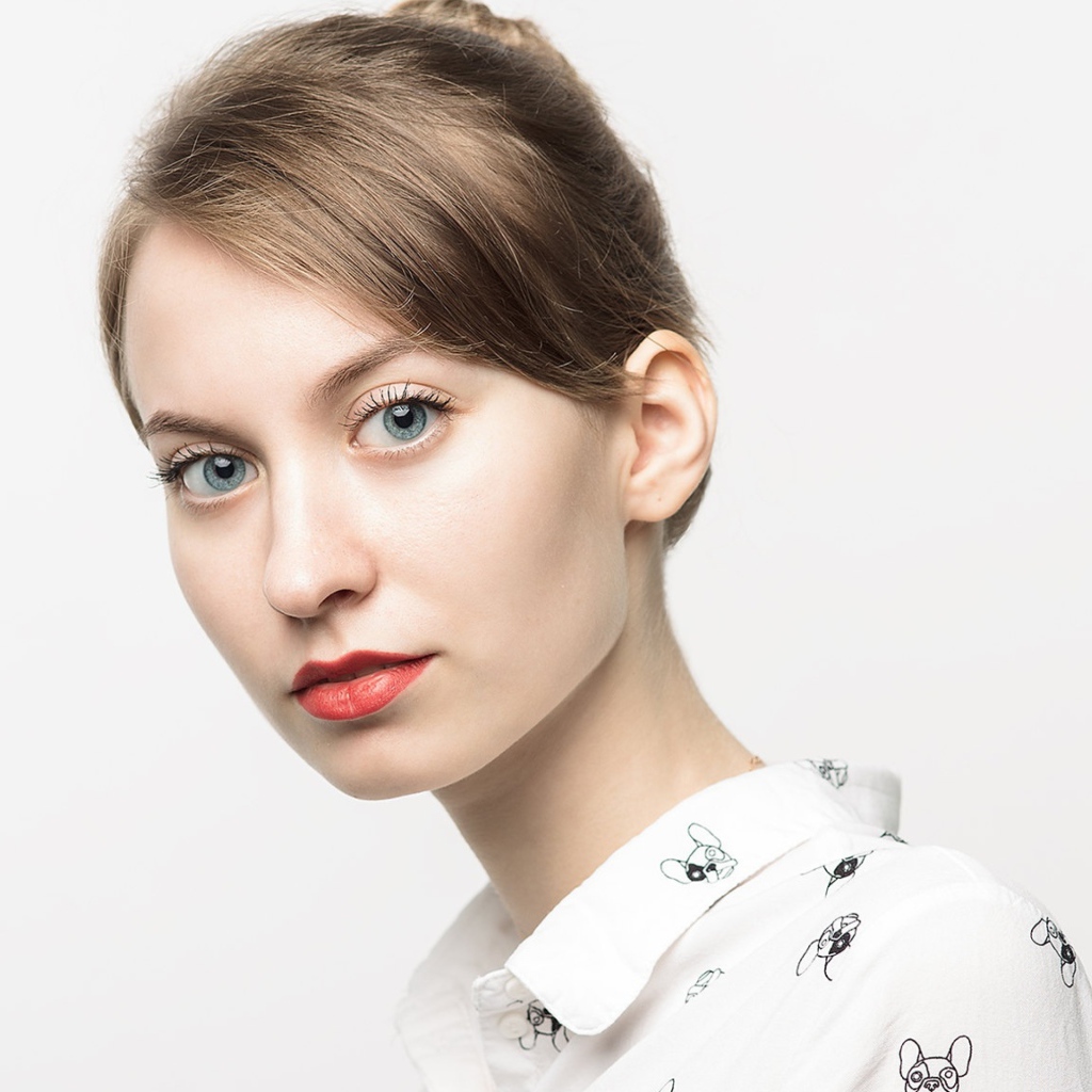 Милая голубоглазая девушка в рубашке на сером фоне