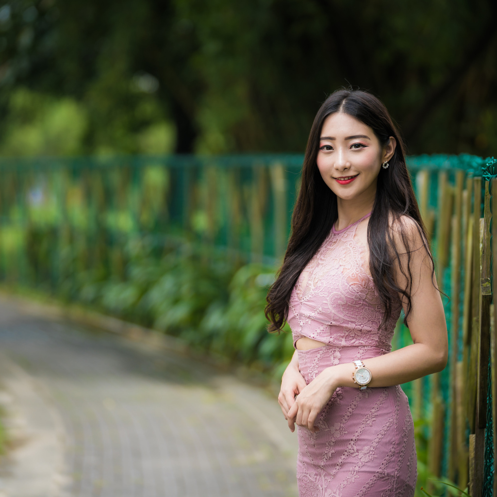 Милая улыбающаяся азиатка в костюме у забора