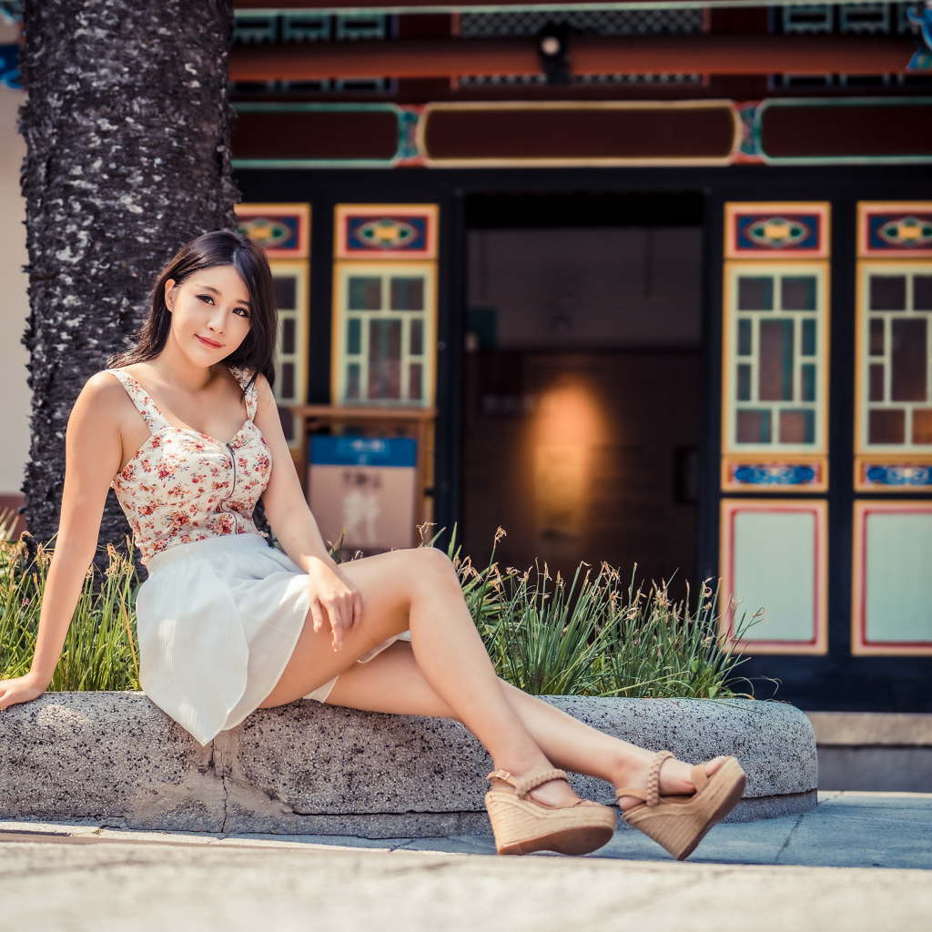 Милая улыбающаяся девушка сидит на бордюре