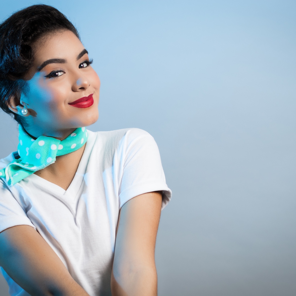 Милая улыбающаяся девушка с шарфом на шее на сером фоне