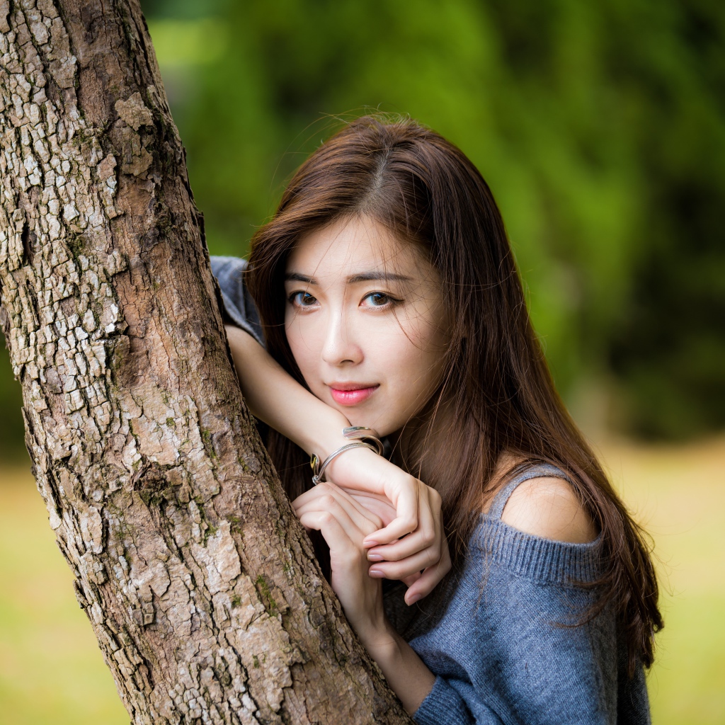 Мечтательная девушка азиатка стоит у дерева