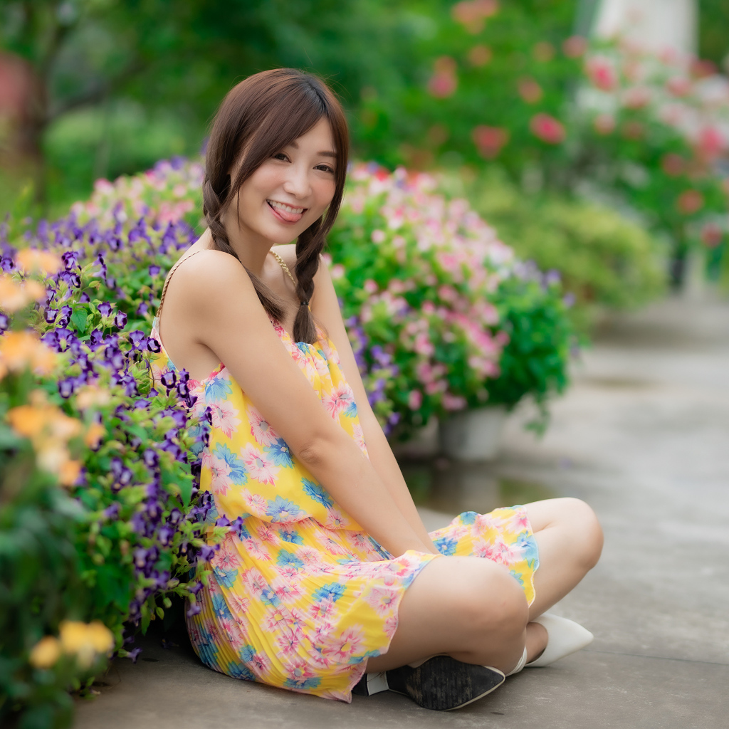 Смешная девушка азиатка в платье сидит на земле