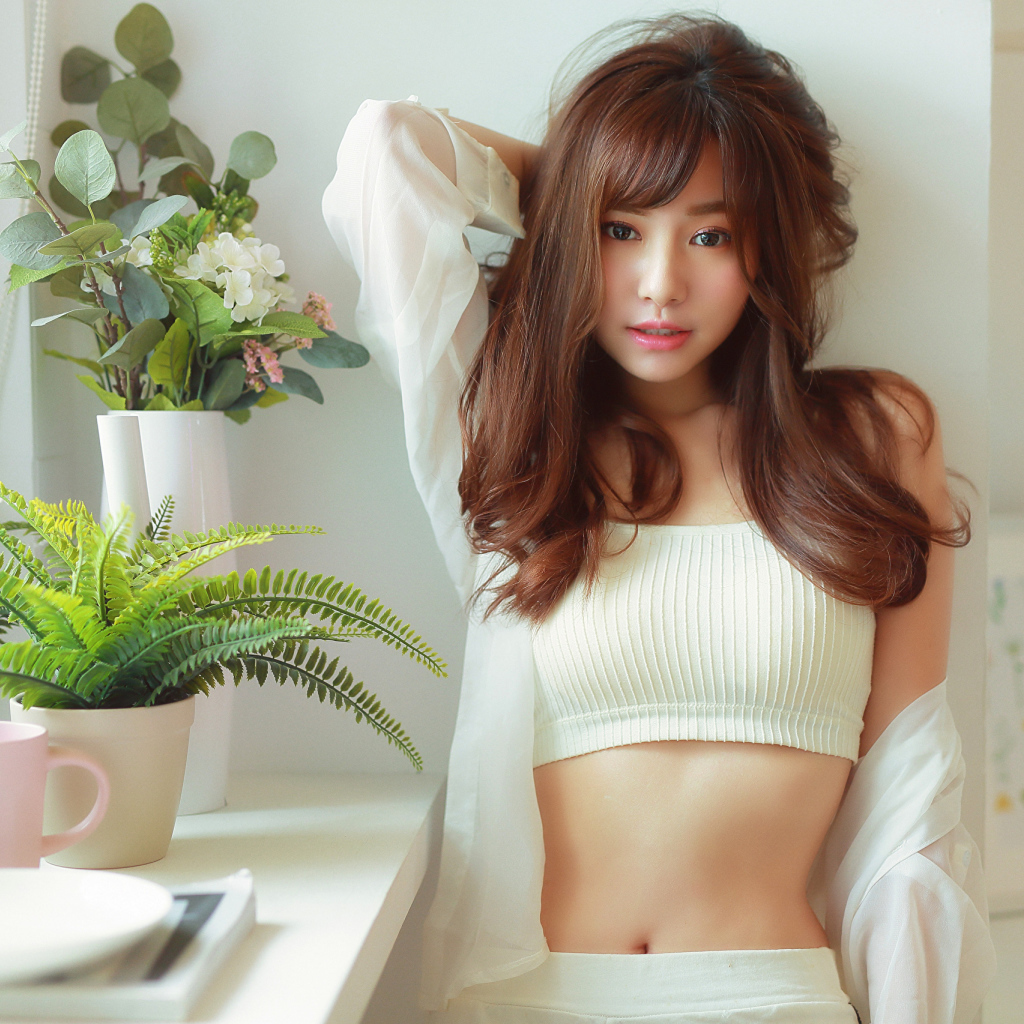 Нежная девушка азиатка стоит у окна